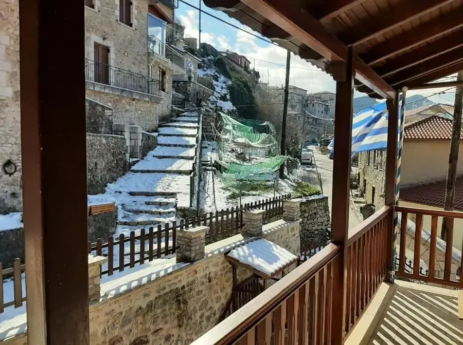 Ξύλινο μπαλκόνι με θέα στα πέτρινα σπίτια και τα σκαλοπάτια του χωριού